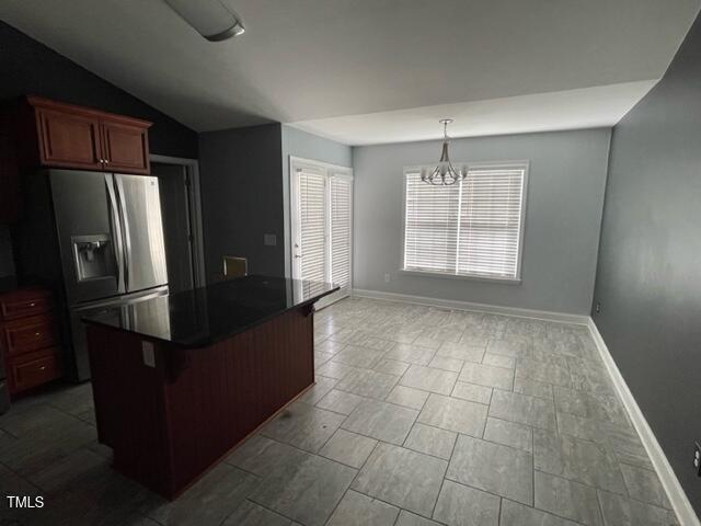 kitchen with lofted ceiling, a breakfast bar, stainless steel fridge, a notable chandelier, and pendant lighting