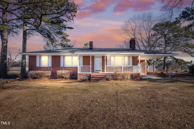 view of front of house featuring a carport, a porch, and a yard