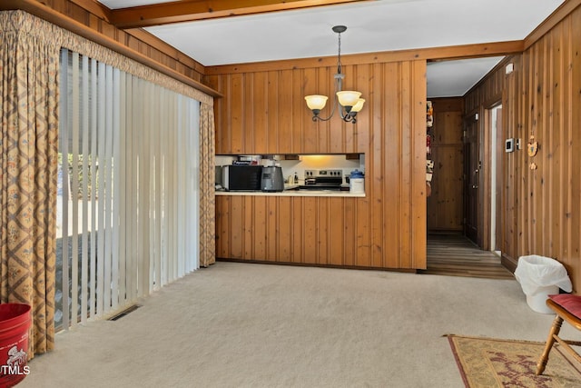 kitchen featuring decorative light fixtures, a chandelier, light carpet, and wood walls