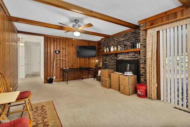 living room featuring a fireplace, wooden walls, carpet floors, ceiling fan, and beam ceiling