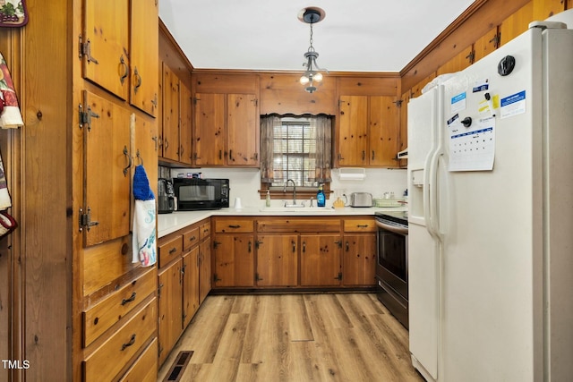 kitchen featuring sink, light hardwood / wood-style flooring, hanging light fixtures, white fridge with ice dispenser, and stainless steel electric range oven