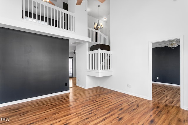 interior space featuring a towering ceiling, ceiling fan with notable chandelier, and hardwood / wood-style floors