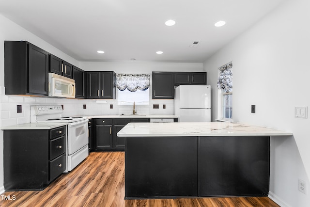 kitchen with sink, white appliances, light hardwood / wood-style flooring, tasteful backsplash, and kitchen peninsula