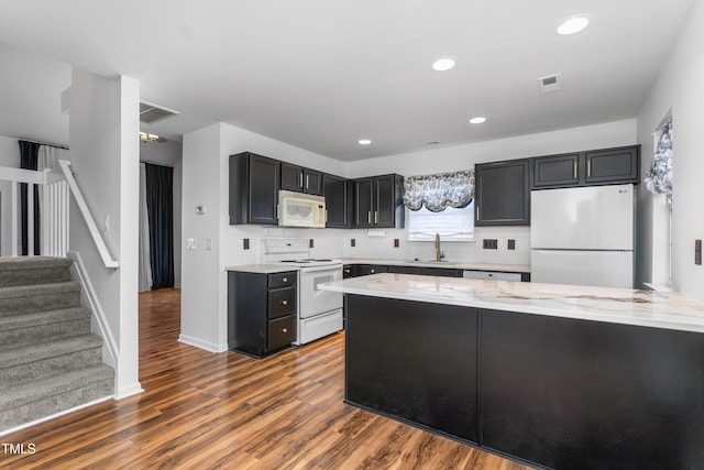 kitchen with sink, light stone counters, dark hardwood / wood-style floors, white appliances, and decorative backsplash