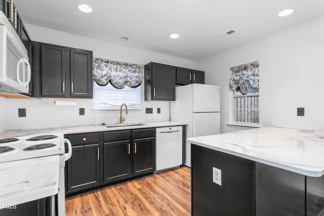 kitchen featuring tasteful backsplash, sink, light hardwood / wood-style floors, light stone countertops, and white appliances