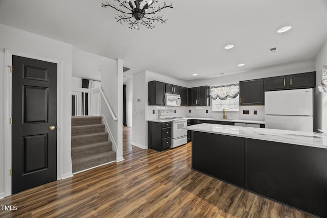 4619 Cross Ridge Ln, Greensboro, NC 27410 - kitchen with white appliances, dark cabinetry, dark wood finished floors, backsplash, and light stone counters