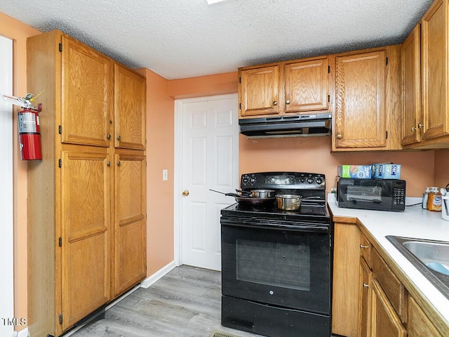 kitchen featuring sink, black range with electric cooktop, a textured ceiling, and light wood-type flooring