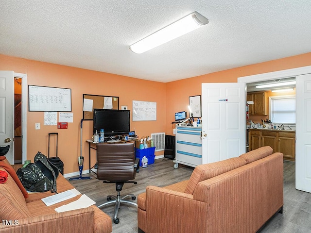 office area featuring hardwood / wood-style floors, sink, and a textured ceiling