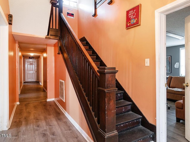 staircase with wood-type flooring and a textured ceiling