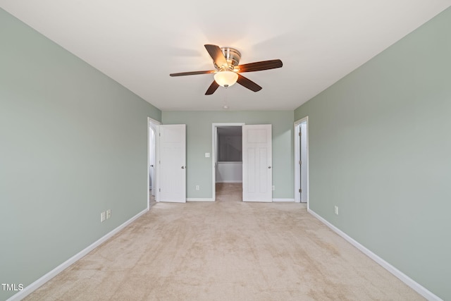 unfurnished bedroom featuring a walk in closet, light carpet, ceiling fan, and a closet