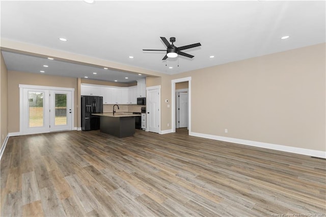 unfurnished living room with baseboards, wood finished floors, ceiling fan, a sink, and recessed lighting