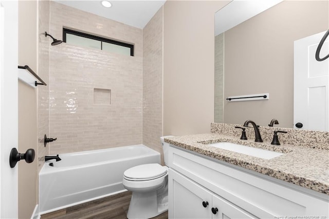 bathroom featuring wood finished floors, toilet, vanity, and shower / tub combination