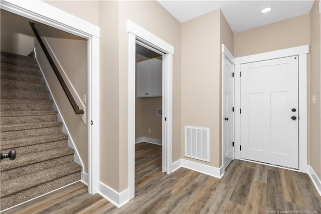 entryway featuring wood finished floors, baseboards, stairs, and recessed lighting