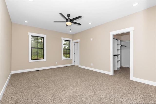 unfurnished bedroom featuring carpet flooring, baseboards, recessed lighting, a spacious closet, and ceiling fan