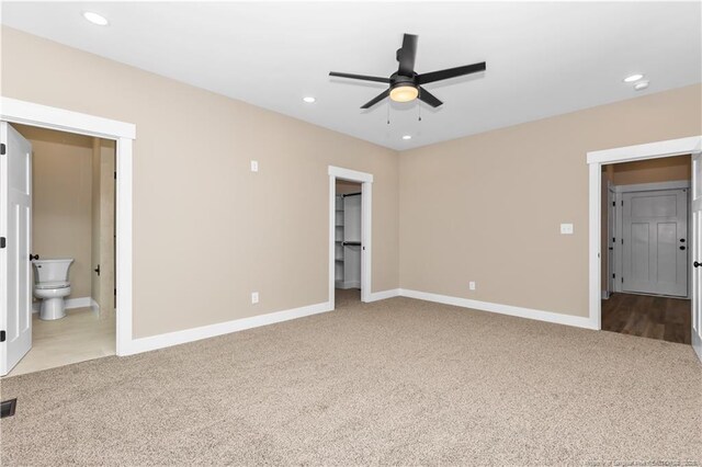 unfurnished bedroom featuring carpet flooring, recessed lighting, baseboards, a walk in closet, and ensuite bath