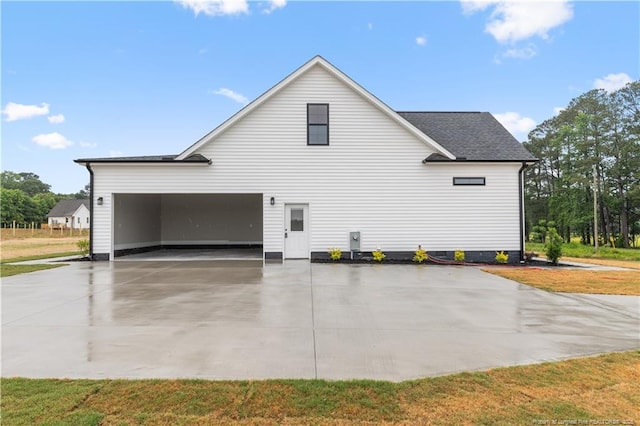 view of side of home featuring driveway, roof with shingles, and a lawn