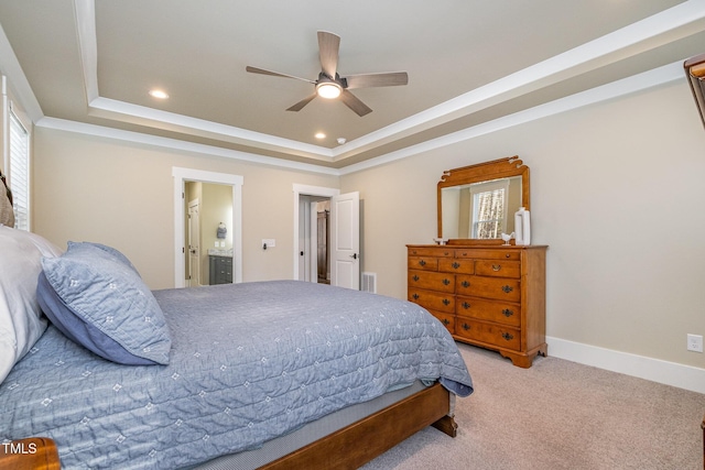 carpeted bedroom with a tray ceiling, ensuite bath, and ceiling fan