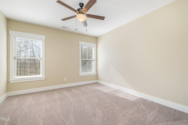 carpeted spare room with ceiling fan and plenty of natural light