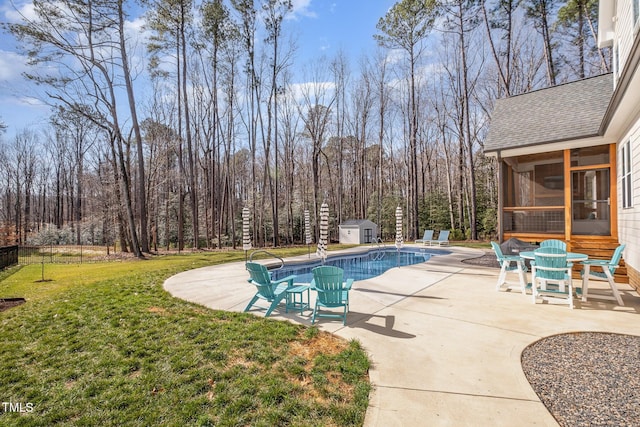 view of pool with a shed, a patio area, a sunroom, and a lawn