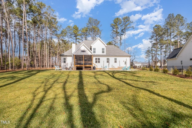 rear view of house with a yard and a sunroom