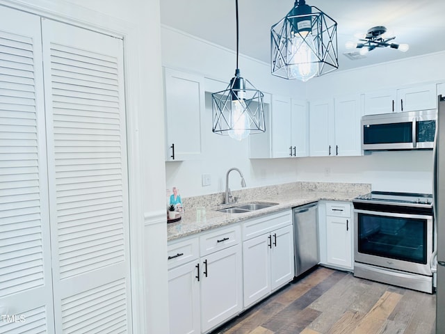 kitchen with sink, appliances with stainless steel finishes, white cabinetry, hanging light fixtures, and dark hardwood / wood-style floors