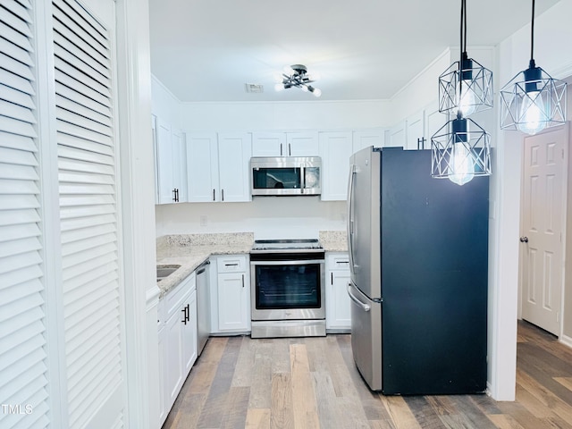 kitchen with white cabinetry, light wood-type flooring, pendant lighting, stainless steel appliances, and light stone countertops