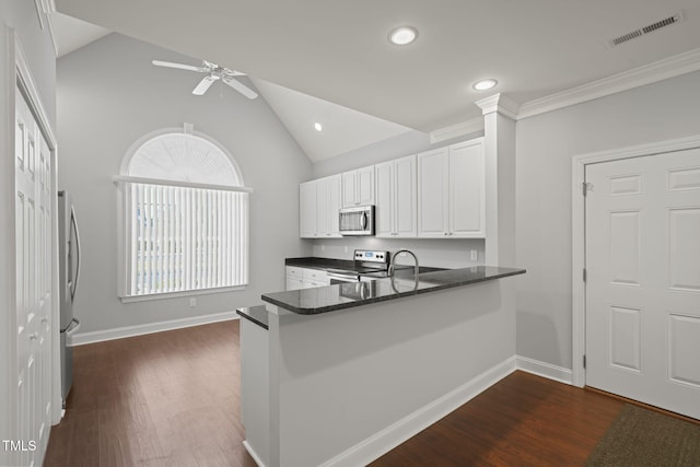 kitchen featuring appliances with stainless steel finishes, white cabinets, dark hardwood / wood-style flooring, vaulted ceiling, and kitchen peninsula