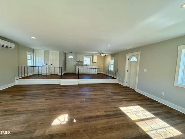 unfurnished living room with wood-type flooring and a wall mounted air conditioner