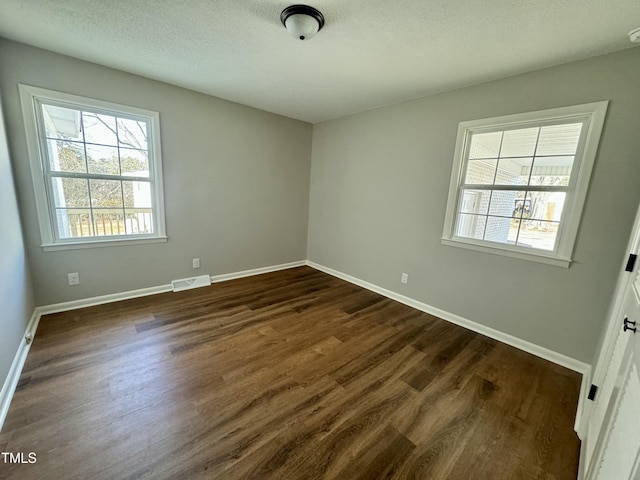 empty room featuring dark wood-type flooring and a textured ceiling