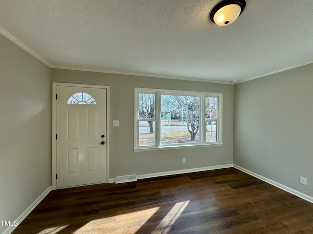 foyer with a healthy amount of sunlight, ornamental molding, dark wood-type flooring, and a textured ceiling