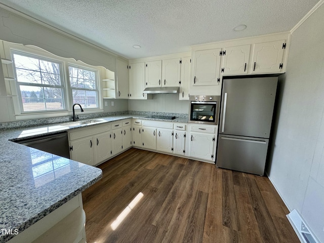 kitchen with sink, appliances with stainless steel finishes, white cabinetry, dark hardwood / wood-style floors, and a textured ceiling