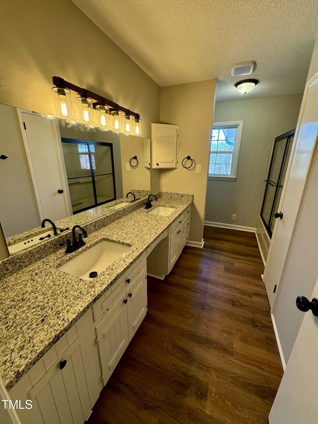 bathroom featuring an enclosed shower, wood-type flooring, vanity, and a textured ceiling