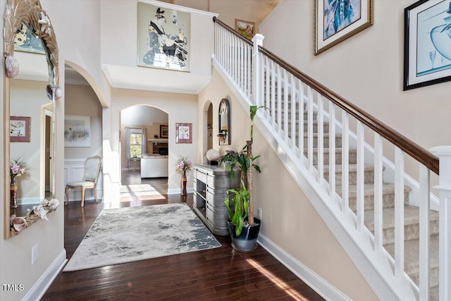 entryway with ornamental molding, wood-type flooring, and a high ceiling