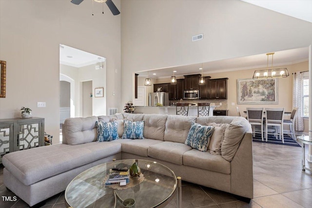 living room featuring tile patterned flooring, crown molding, a towering ceiling, and ceiling fan