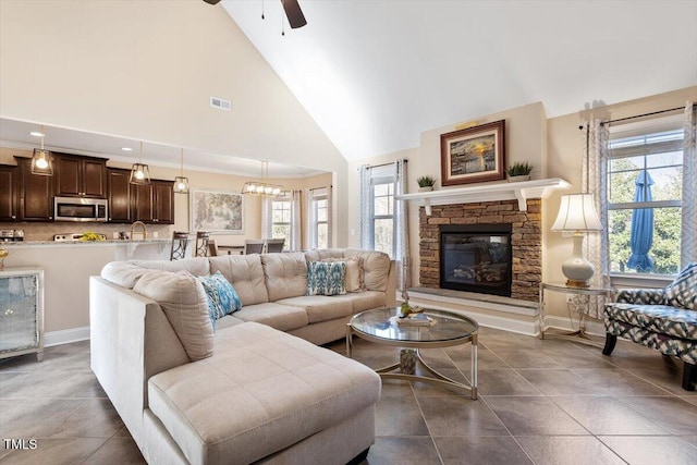 living room featuring a fireplace, dark tile patterned flooring, high vaulted ceiling, and a wealth of natural light