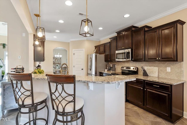 kitchen with backsplash, decorative light fixtures, a kitchen breakfast bar, and appliances with stainless steel finishes