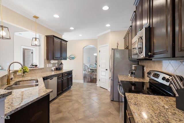 kitchen with appliances with stainless steel finishes, pendant lighting, sink, light stone counters, and dark brown cabinets