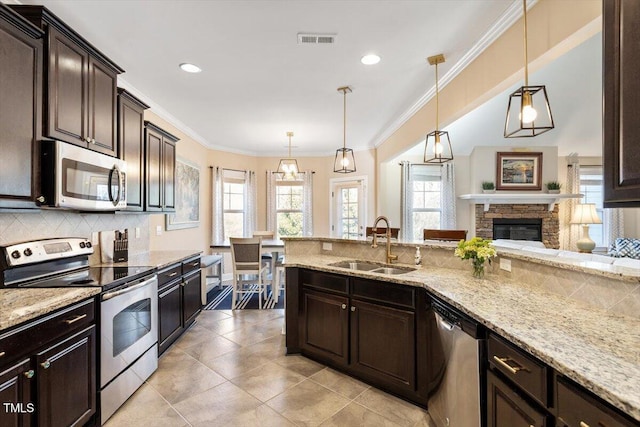 kitchen featuring appliances with stainless steel finishes, pendant lighting, sink, decorative backsplash, and dark brown cabinets