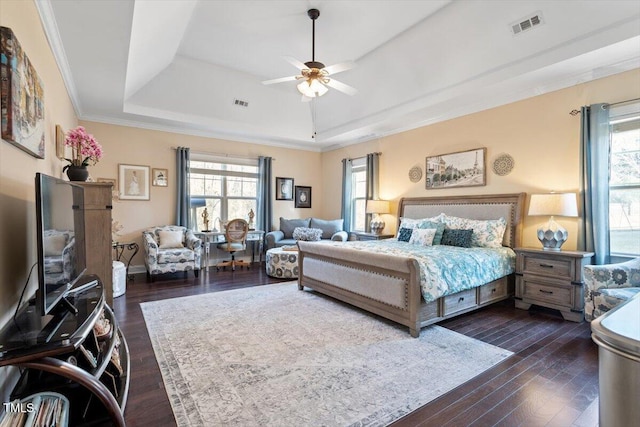 bedroom featuring multiple windows, dark hardwood / wood-style floors, crown molding, and a raised ceiling