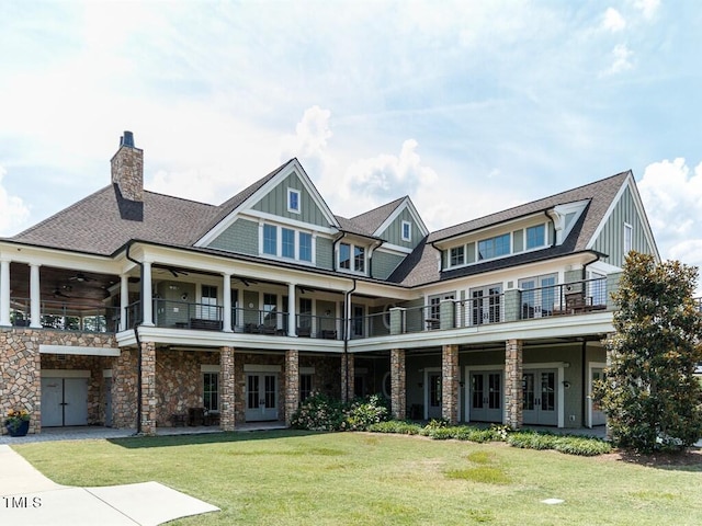 craftsman-style house featuring french doors, a balcony, ceiling fan, and a front yard