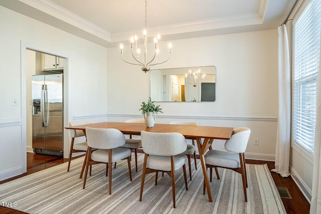 dining area featuring ornamental molding, a tray ceiling, and hardwood / wood-style floors