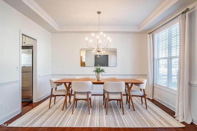 dining room with crown molding, a raised ceiling, and hardwood / wood-style flooring