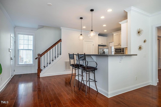 kitchen with a breakfast bar area, white cabinetry, decorative light fixtures, kitchen peninsula, and stainless steel appliances