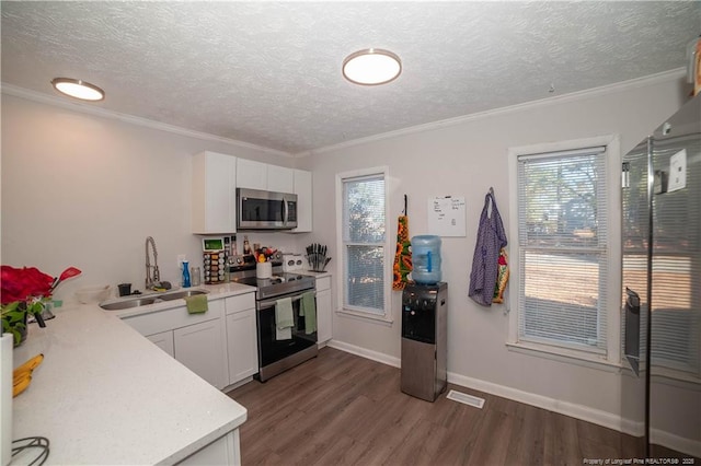 kitchen with dark wood-type flooring, sink, crown molding, stainless steel appliances, and white cabinets