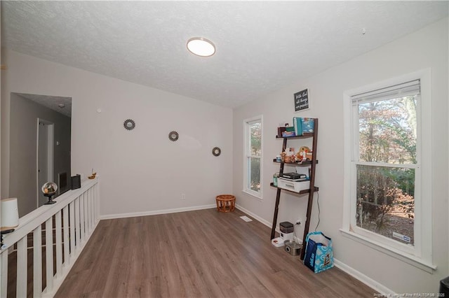 unfurnished room with hardwood / wood-style flooring and a textured ceiling