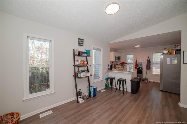 kitchen featuring lofted ceiling, a breakfast bar, white cabinetry, kitchen peninsula, and stainless steel appliances