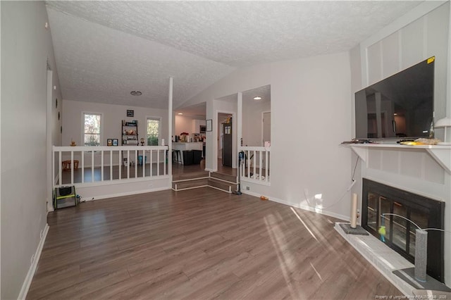 unfurnished living room featuring hardwood / wood-style flooring, vaulted ceiling, and a textured ceiling