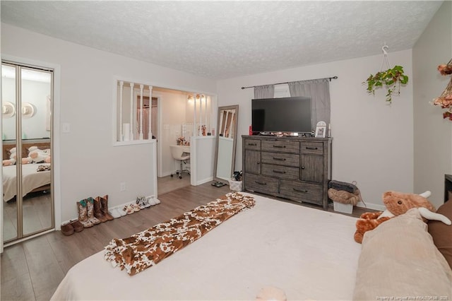 bedroom featuring ensuite bath, light hardwood / wood-style floors, and a textured ceiling