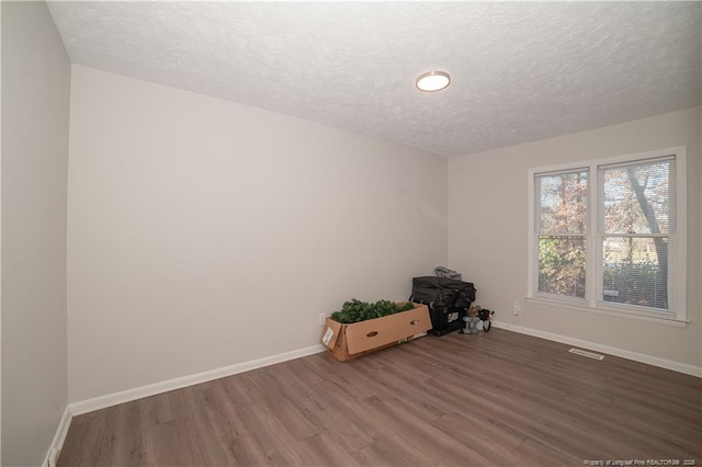 unfurnished room with hardwood / wood-style floors and a textured ceiling