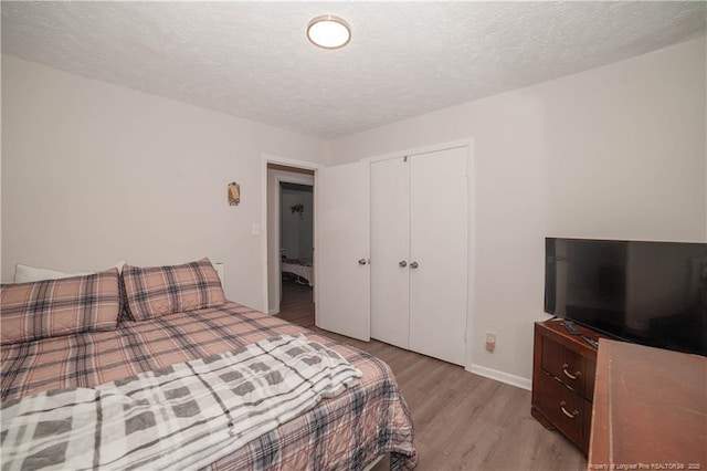 bedroom with a textured ceiling, a closet, and light wood-type flooring